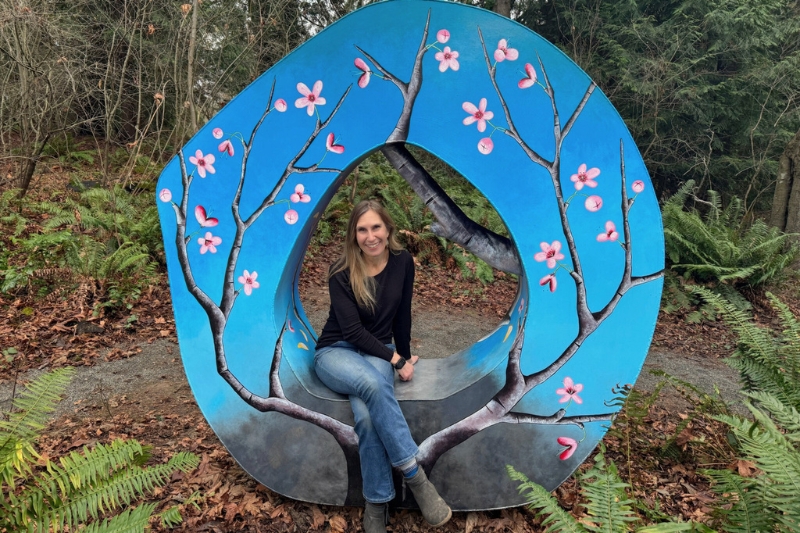 Christine Loewe sitting the sculpture a seat in the woods by Jennifer Kapnek in Websters Woods Sculpture park.